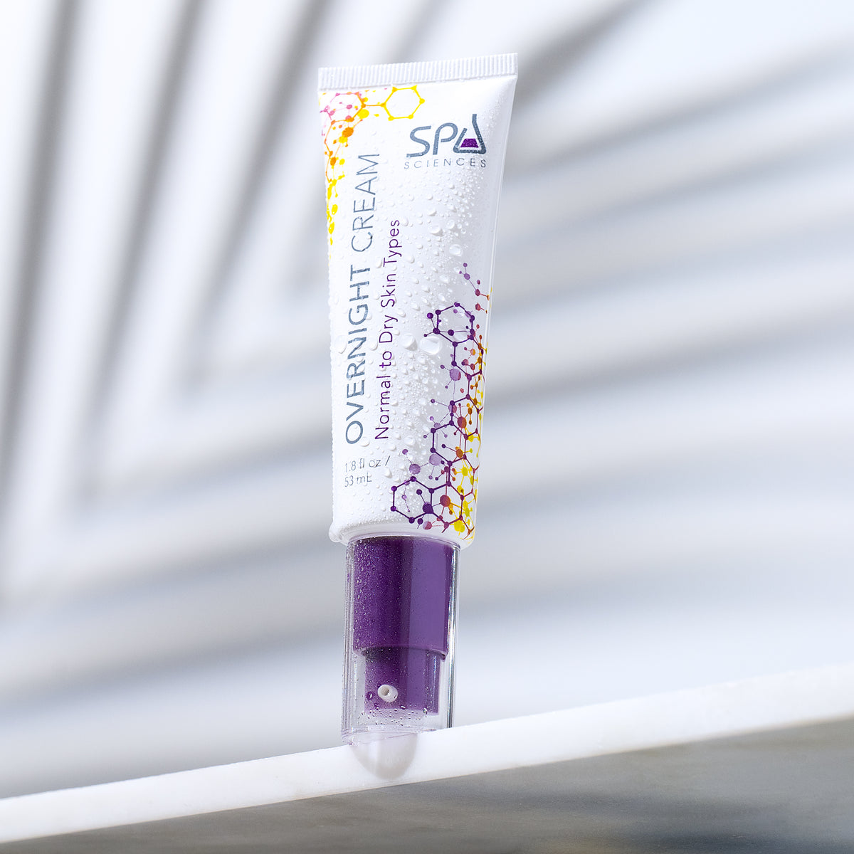 A tube of Retinol Renewal Kit (Dry Skin) overnight cream with a purple pump dispenser, covered in water droplets.