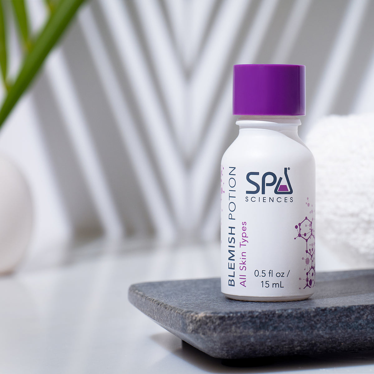 Small bottle of Blemish Rescue Kit blemish treatment with a purple cap, sitting on a stone tray.