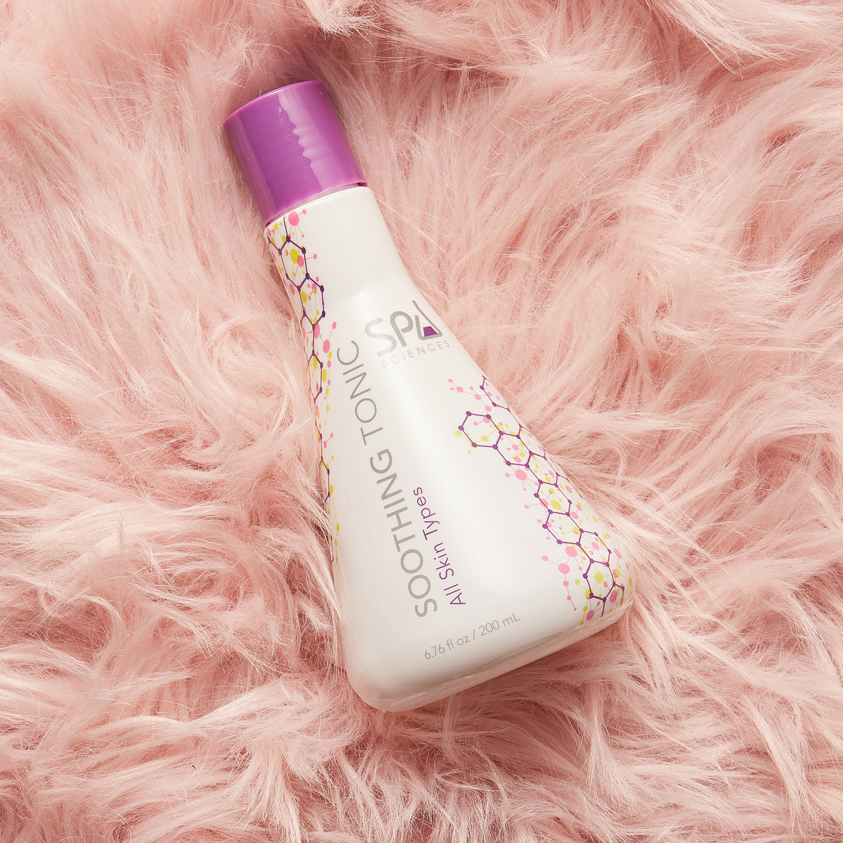 A Blemish Rescue Kit soothing tonic bottle with a purple cap rests on a pink faux-fur surface.