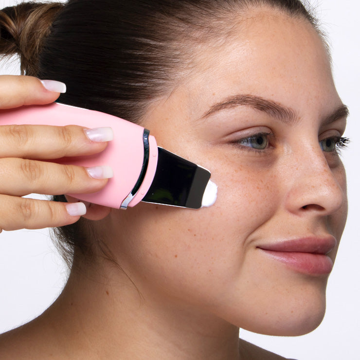 A woman is applying Spa Sciences Acne Attack Bundle facial cleanser to her face.