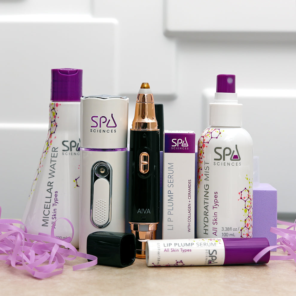 A collection from Spa Sciences called the "On the Go Set," featuring skincare essentials such as micellar water, hydrating mist, lip plump serum, and an electronic skincare device, all beautifully encased in decorative purple paper.