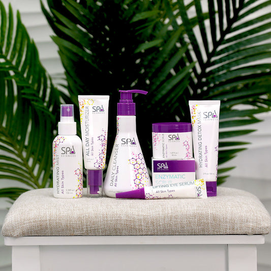 A collection of Spa Sciences' Starter Pack for All skincare products arranged on a cushion with a plant in the background.
