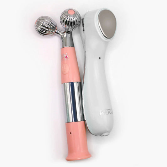 The Spa Sciences Ultimate Moisture Bundle features two handheld facial devices—one pink and silver with dual rollers, and one white with a flat treatment surface—displayed side by side on a white background.
