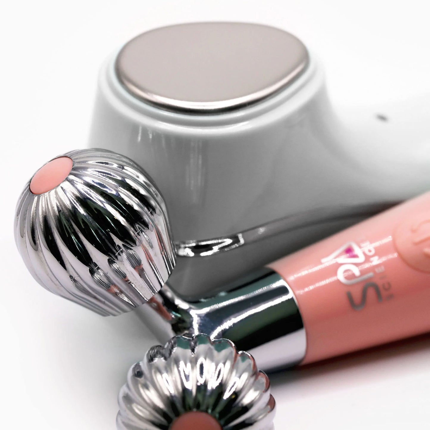 Close-up of the Spa Sciences Ultimate Moisture Bundle—two pink and metallic handheld facial massage and skincare devices—on a white surface.