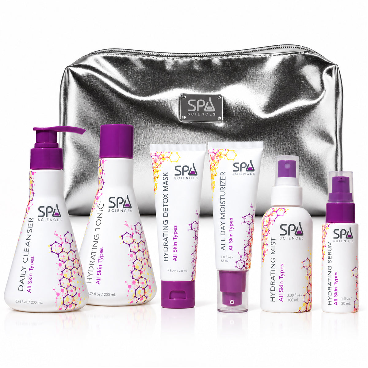 The Spa Sciences Ultimate Self-Care Set features six skincare products in pump and squeeze bottles with purple caps, arranged in front of a metallic silver cosmetic bag.