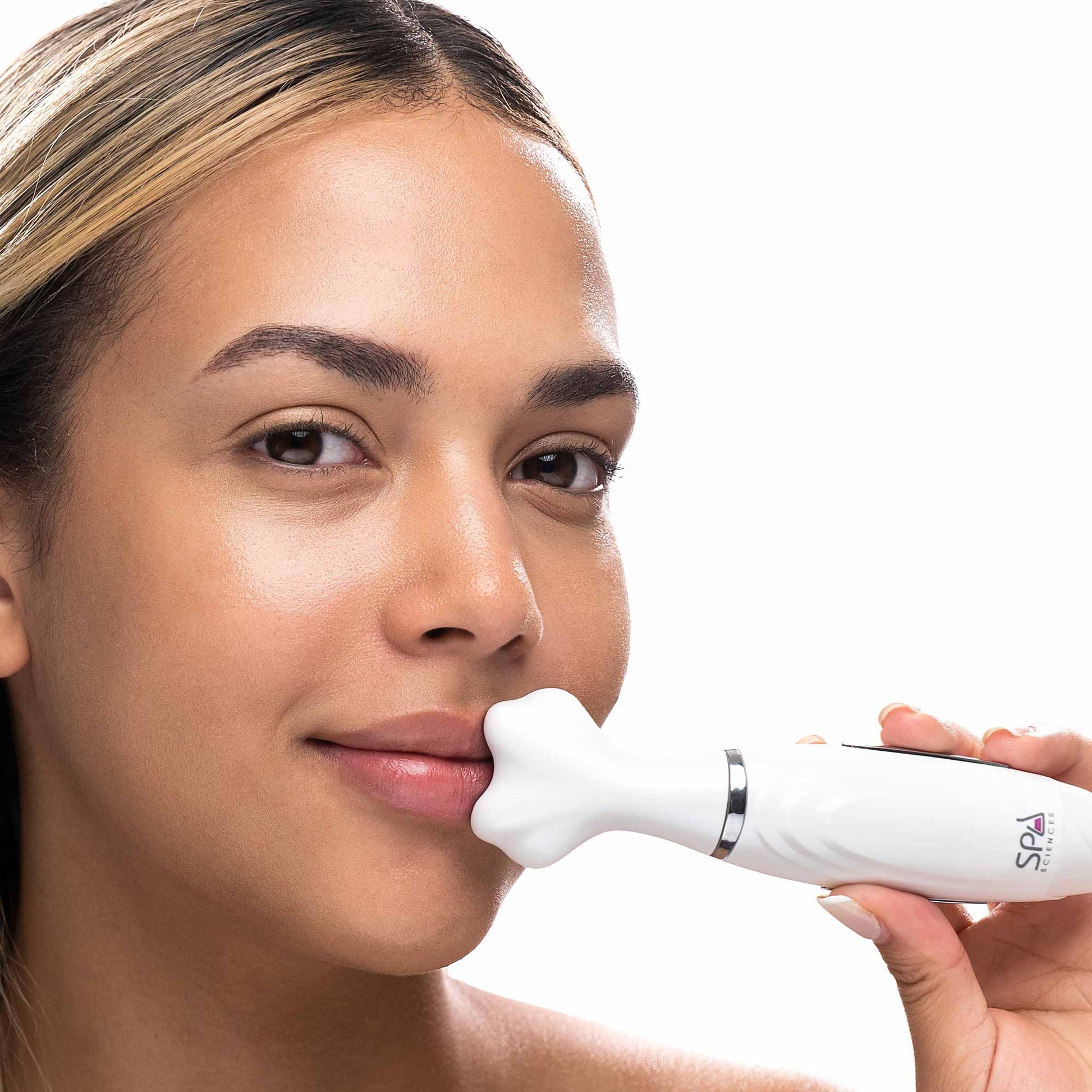 A woman is using a LORI Sonic Wand by Spa Sciences to promote blood circulation on her face.