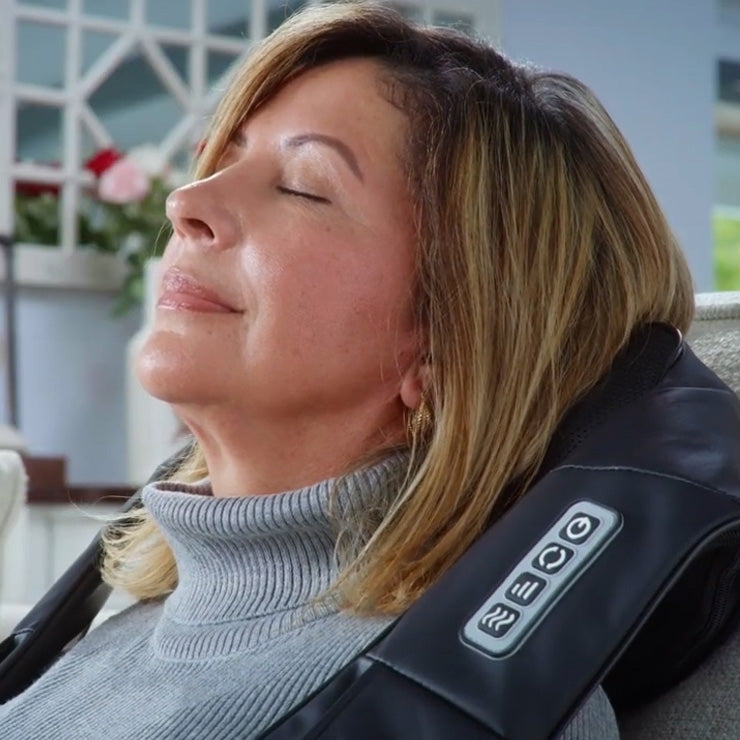 A woman is reclining on a Spa Sciences TESA massage chair with her eyes closed.