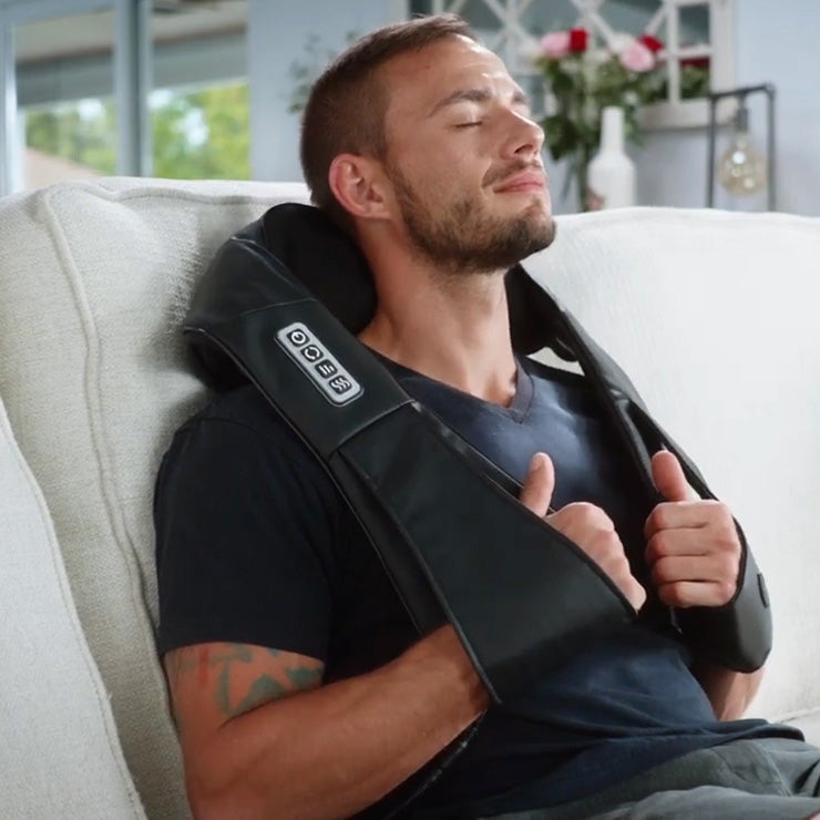 A man lounging on a couch with a Spa Sciences TESA neck massager.