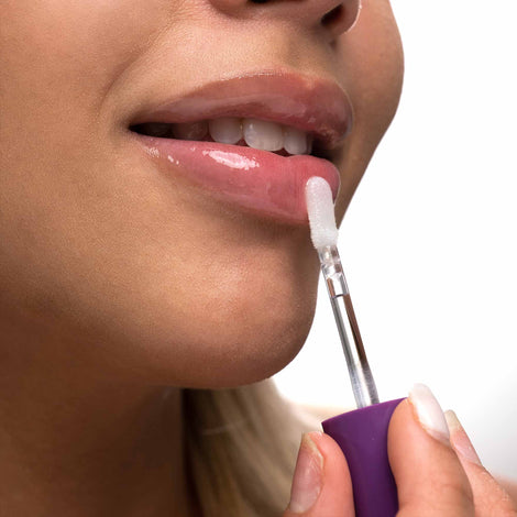 A woman is applying Spa Sciences' Lip Plump Serum to her lips.