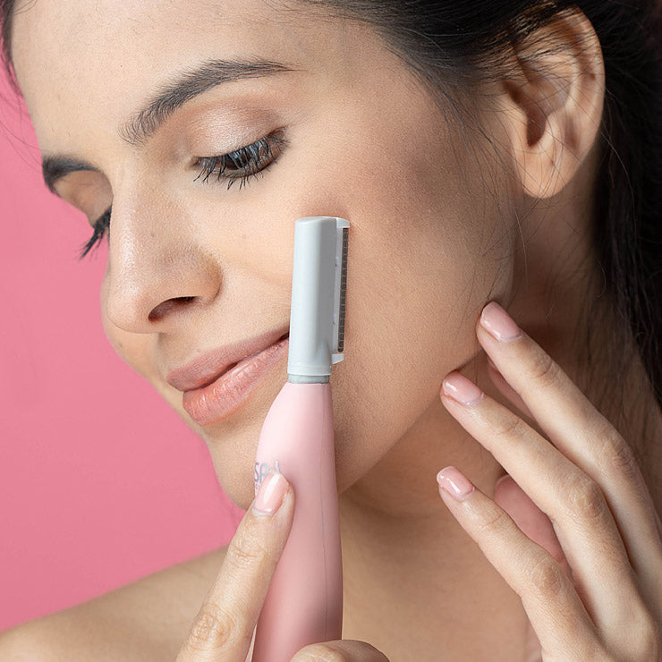 A woman is using the Spa Sciences SIMA Deluxe Kit electric shaver on her face.